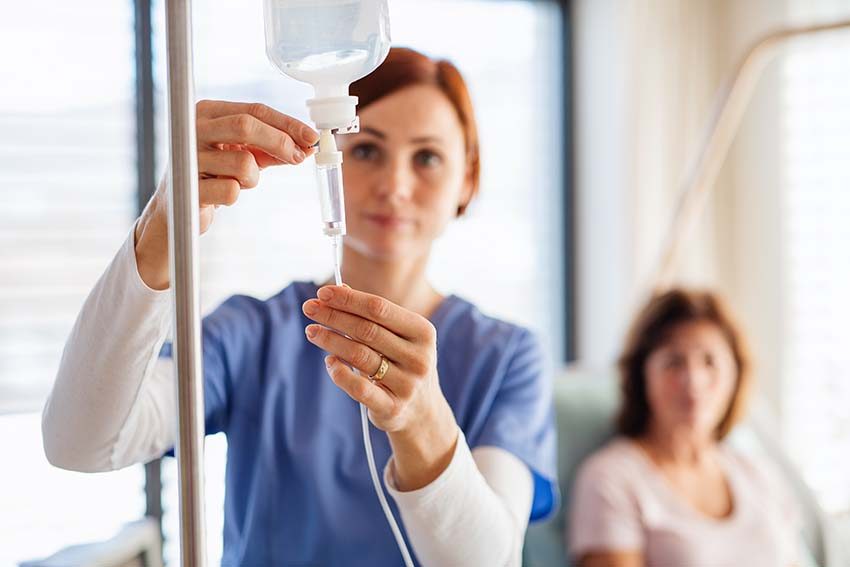 A nurse adjusting an IV drip bag beside a treatment chair — IV therapy in McAllen, TX